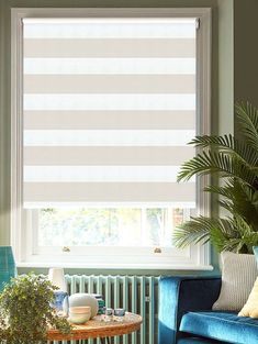 a living room filled with furniture and a window covered in roman shades on the windowsill