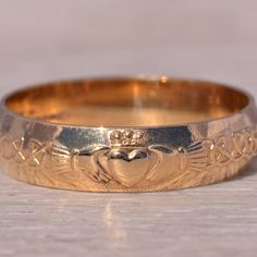 a gold wedding band with an image of a heart on it