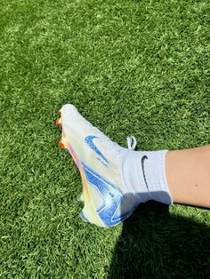 a person's foot wearing white and blue socks on green grass in the sun