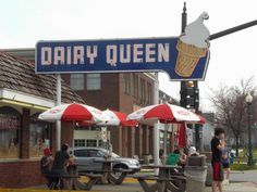 people sitting at tables under umbrellas in front of a dairy queen sign