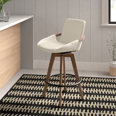 a white bar stool sitting on top of a black and white rug next to a counter