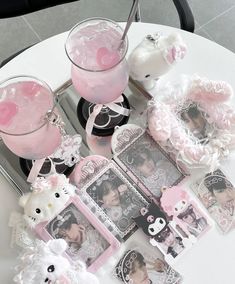 a table topped with pictures and teddy bears next to a glass filled with pink liquid