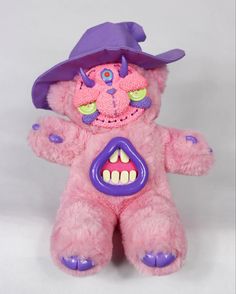 a pink teddy bear wearing a purple hat