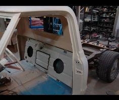 the inside of a car with its door open in a workshop area filled with tools