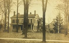 an old photo of a large house in the middle of some trees and leaves on the ground