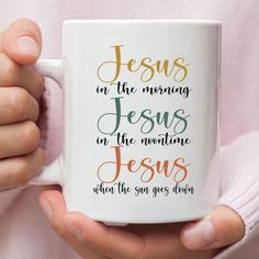 a person holding a coffee mug with the words jesus on it in gold and red