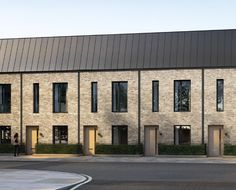 the building has many windows and doors on each side, along with two parking spaces