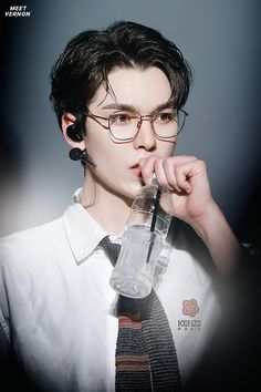 a young man wearing glasses and holding a water bottle