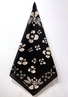 a black bandana with white flowers on it hanging from a hook in the wall