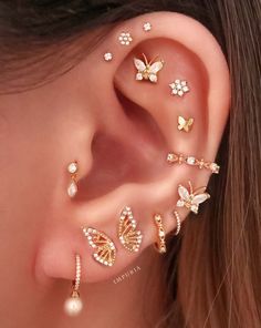 a woman wearing gold ear piercings with butterflies and pearls