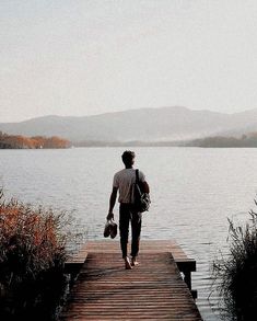 a man walking down a dock towards the water