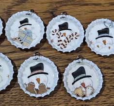 six snowman bottle cap ornaments on a wooden table