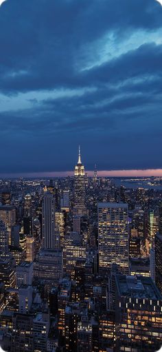 an aerial view of the city at night with skyscrapers lit up and clouds in the sky