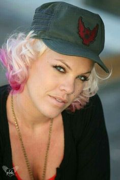 a woman with pink hair wearing a hat