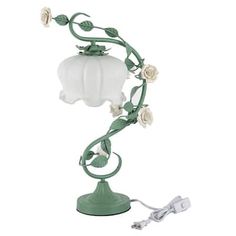 a green table lamp with white flowers on the base and a cord attached to it