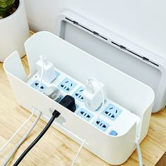 an electrical outlet box with multiple plugs in it on a table next to a potted plant