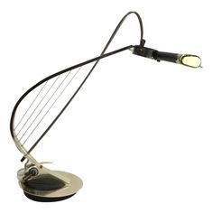 a metal table lamp that is on top of a white surface with a black handle