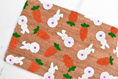 a door mat with carrots and bunny ears on it, sitting on a white surface