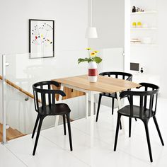 a dining room table with four chairs and a plant in a vase on the table