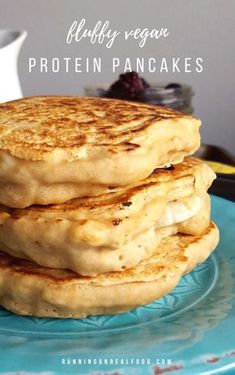 pancakes stacked on top of each other on a blue plate with fruit in the background