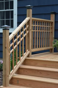 a wooden deck with railing and planter in front of a blue house on a sunny day