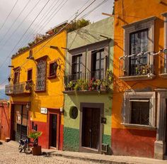 an image of a street scene with buildings painted in different colors and plants on the balconies