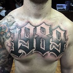 a man with tattoos on his chest has the word god written in black and grey ink