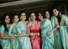 a group of women standing next to each other in sari's and smiling at the camera