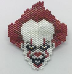 a red and white beaded brooch with a clown face