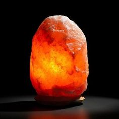 a large orange rock sitting on top of a table next to a black background with light coming from it