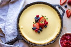 a cheesecake with strawberries and blueberries on top is sitting in a pan