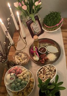 a table topped with plates and bowls filled with food next to candles on top of a table