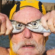 an older man holding up two fish in front of his eyes