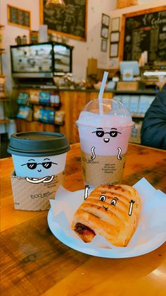 a hot dog and two cups of coffee on a table in a cafe, with faces drawn on them