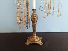 a gold colored table lamp with lots of necklaces hanging from it's sides