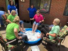 several women are sitting in chairs around a large blue tub filled with foam and water