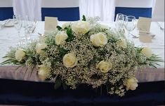 white roses and baby's breath are arranged on the center piece of a table