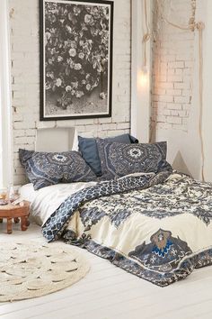 a bed with blue and white comforter in front of a painting on the wall