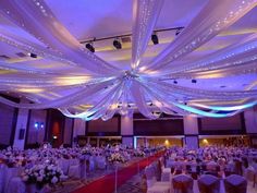 a banquet hall decorated with white and red linens, draping and flowers