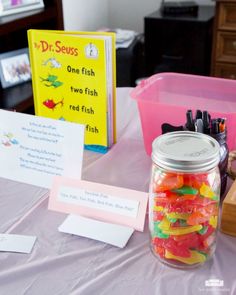 a jar filled with gummy bears sitting on top of a table next to a book