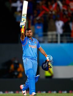 a man in blue uniform holding up a bat and glove while standing on top of a field