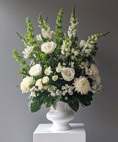 a white vase filled with lots of white flowers