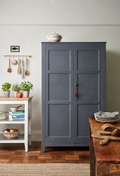 a blue cabinet sitting in the corner of a room next to a table with plates and bowls on it