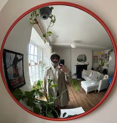 a man is taking a selfie in the mirror with his cell phone and houseplant