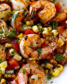 shrimp, corn and tomato salad on a white plate with the words cookin'fever written above it