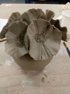 a clay flower sitting on top of a wooden table