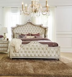 a white bed sitting on top of a carpet covered floor next to a chandelier