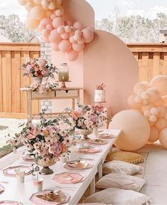 an outdoor party with balloons and flowers on the table, along with plates and utensils