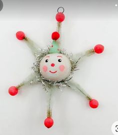 a christmas ornament hanging from the ceiling with red balls and tinsel on it