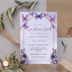 a wedding card with purple flowers and butterflies on it, next to some gold foil